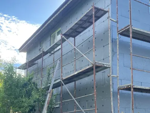Dış cephesi grafitli yalıtım levhalarıyla kaplanmış ve dübellenmiş ev, önünde iş iskelesi