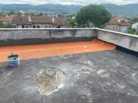 Teras çatıda parapet diplerine serilmiş turuncu donatı filesi ve bozuk bölgesi kazınmış eski zemin